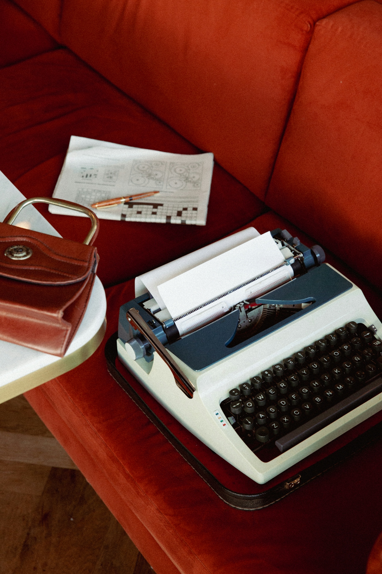 Typewriter and a paper on a seat, with a purse nearby on a table