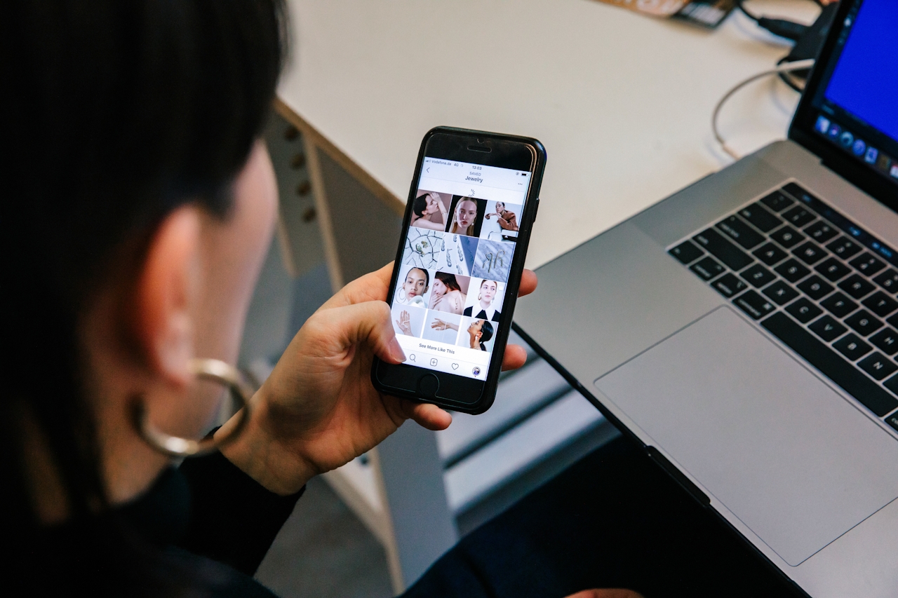 A woman looks down at her phone, showing a social media feed